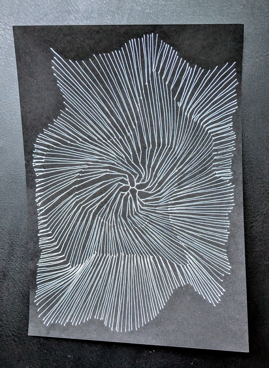 Weiße radiale Linienzeichnung auf schwarzem Papier, zentriert und spiralförmig ausgerichtet